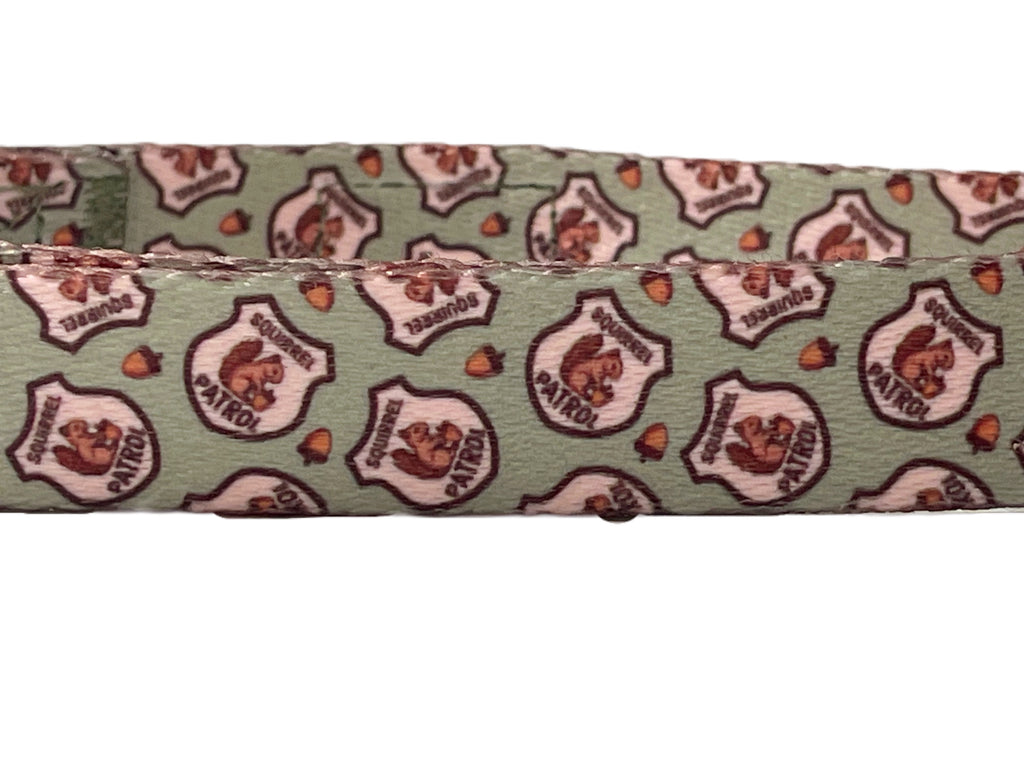 A dog collar with a squirrel patrol badge pattern, showcasing the durable metal hardware and adjustable nature of the collar.