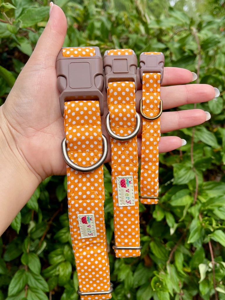 Handmade peach polka dot pet collars with soft brown buckles and eco-friendly fabric, shown against green leaves