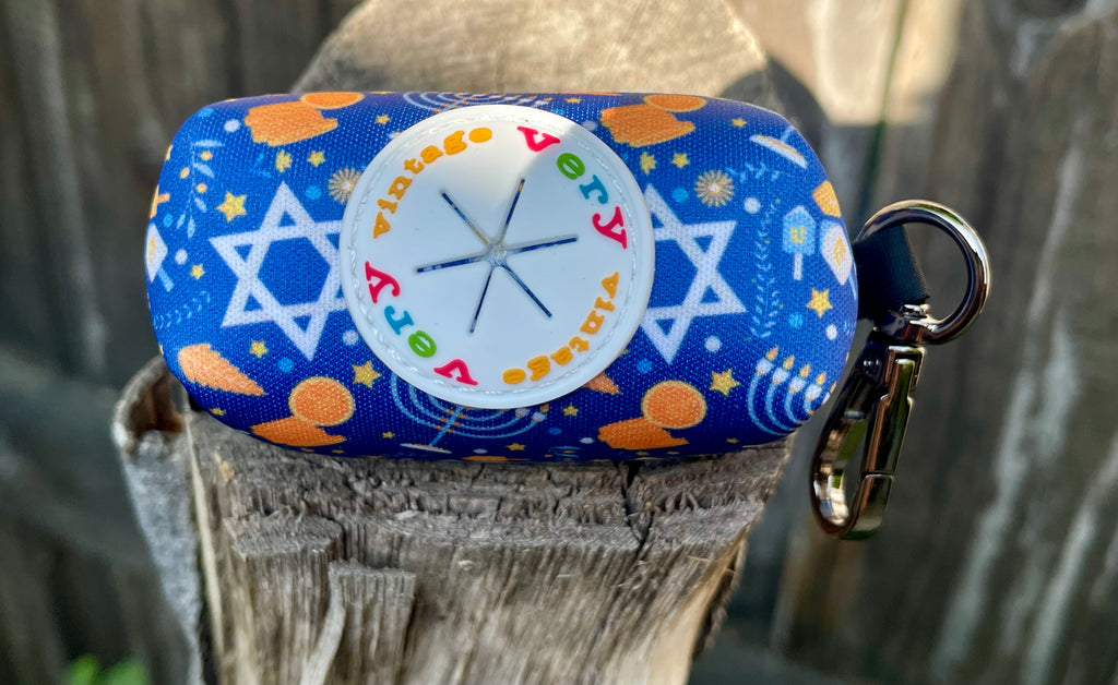 Close-up of the rubber dispenser port on the Hanukkah poop bag holder, surrounded by golden coins and holiday motifs