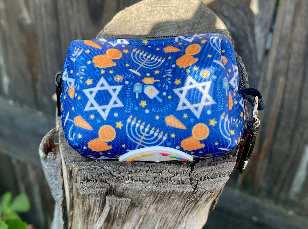 Hanukkah dog poop bag holder sitting on a rustic stump, showcasing blue and gold holiday icons including menorahs and stars