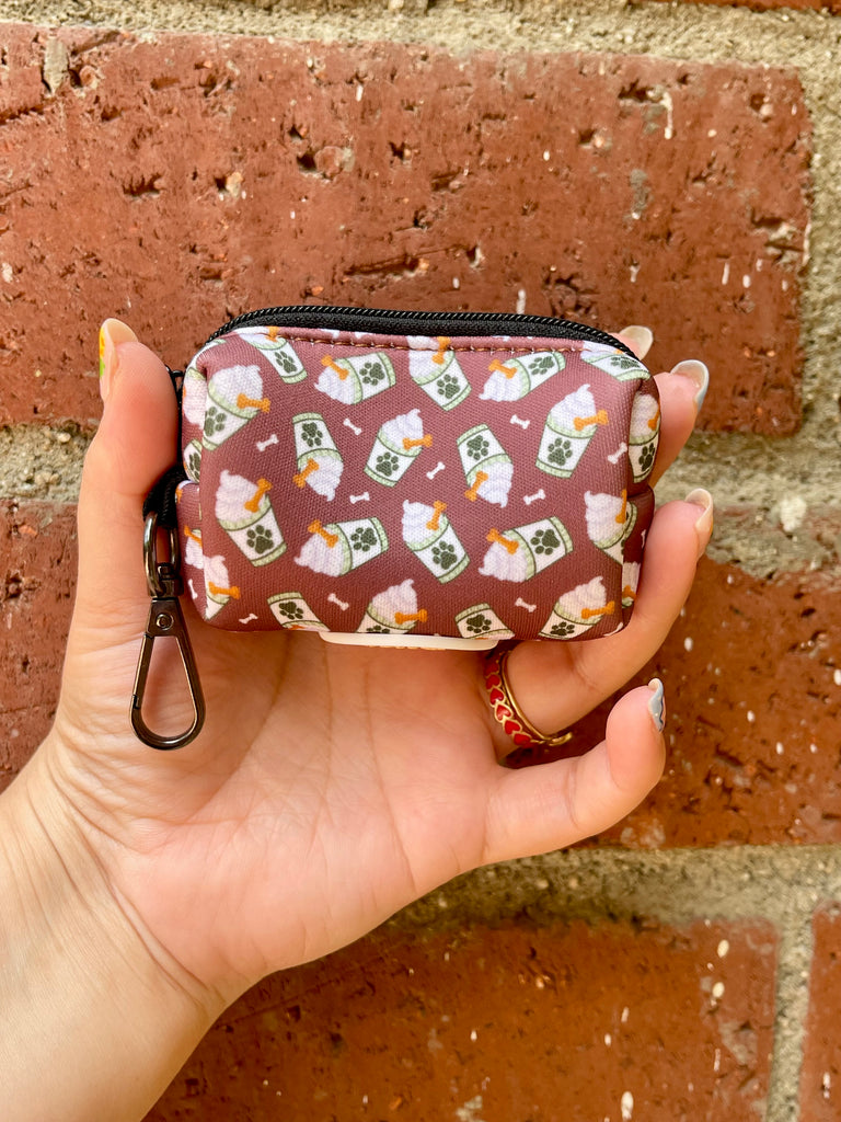 Puppachino poop bag holder shown against red brick wall, emphasizing color and coffee-themed print