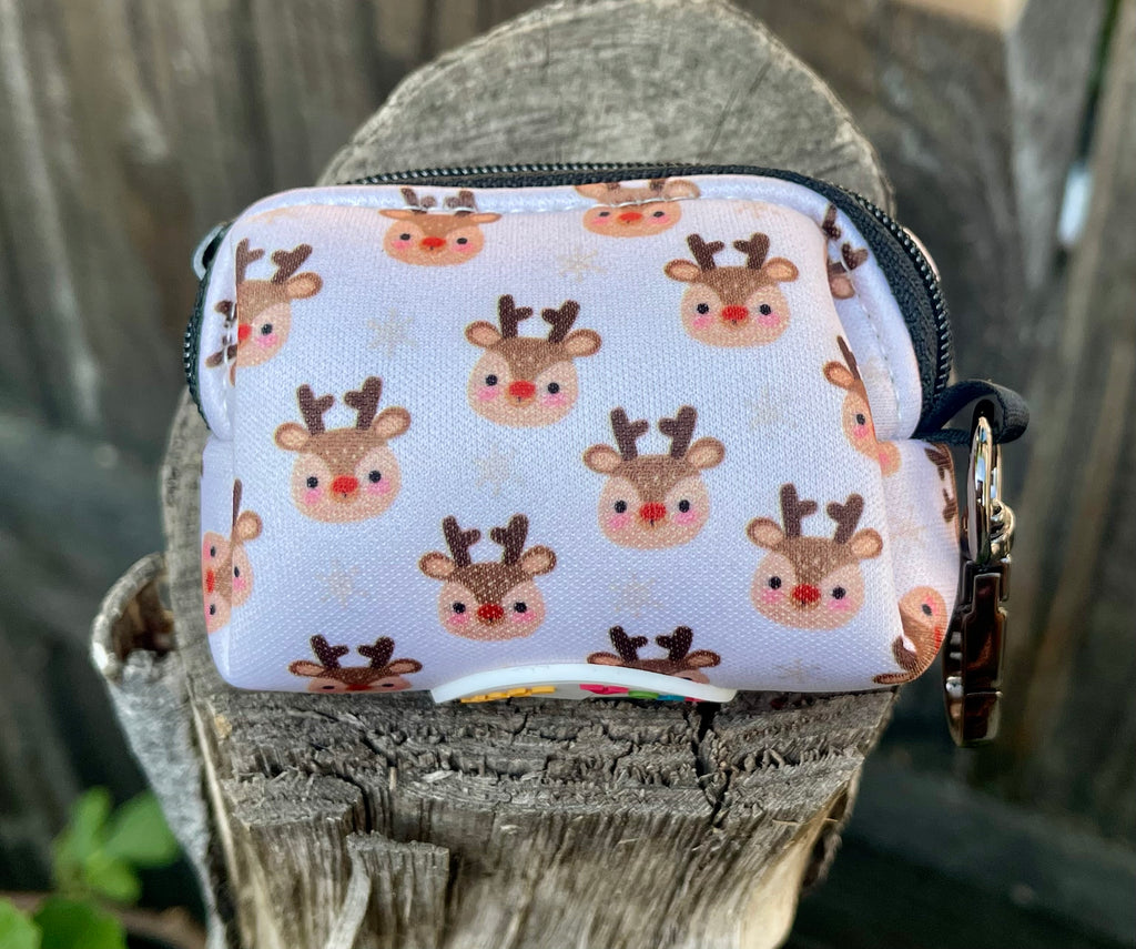 Christmas-themed dog poop bag holder sitting on a weathered wooden stump, featuring adorable reindeer print