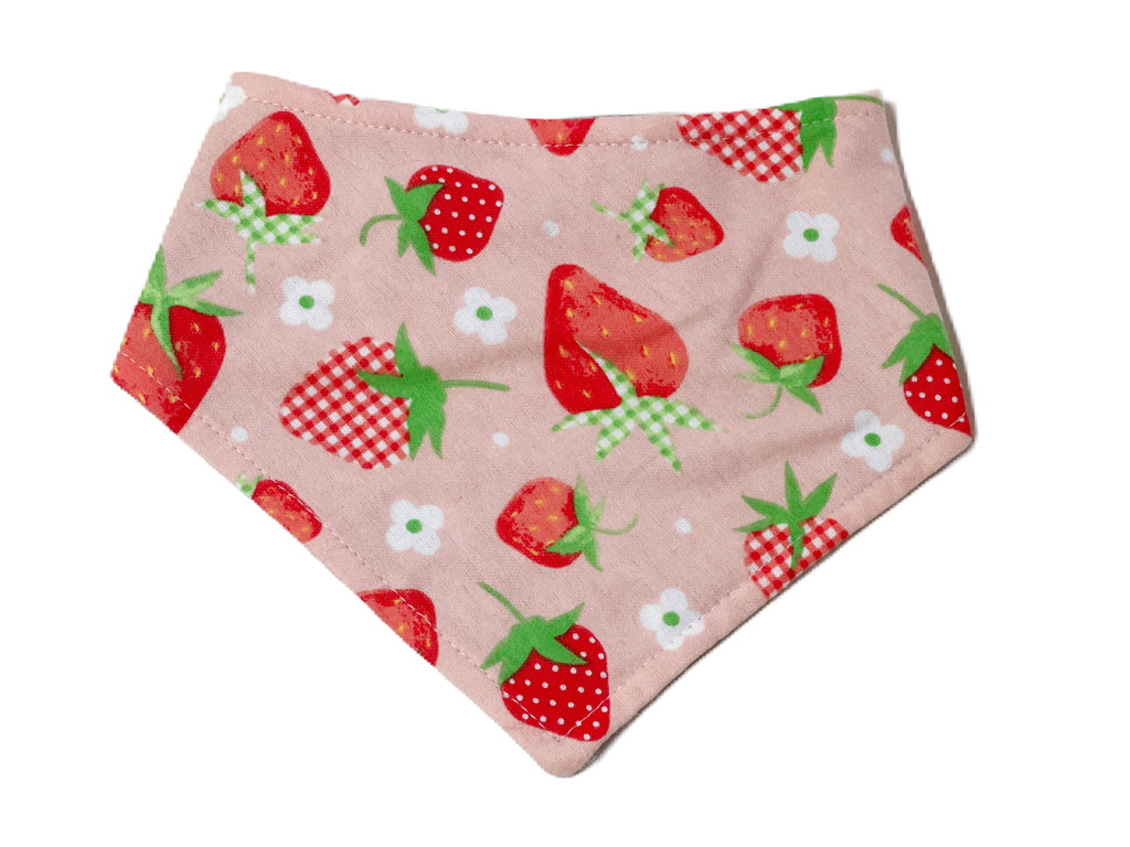 A light pink background covered with red and plaid strawberries and white daisies cotton dog bandana. Handmade in Sunny California.