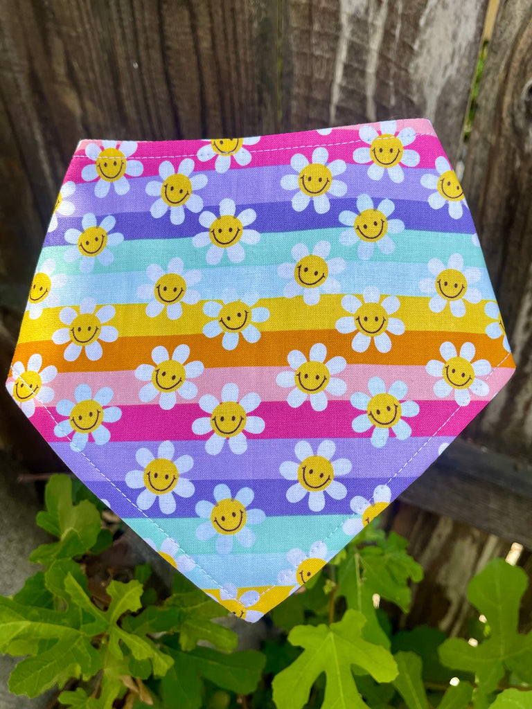 Rainbow Daisies bandana laid flat showing full pattern of pastel stripes and cheerful yellow smiley flowers