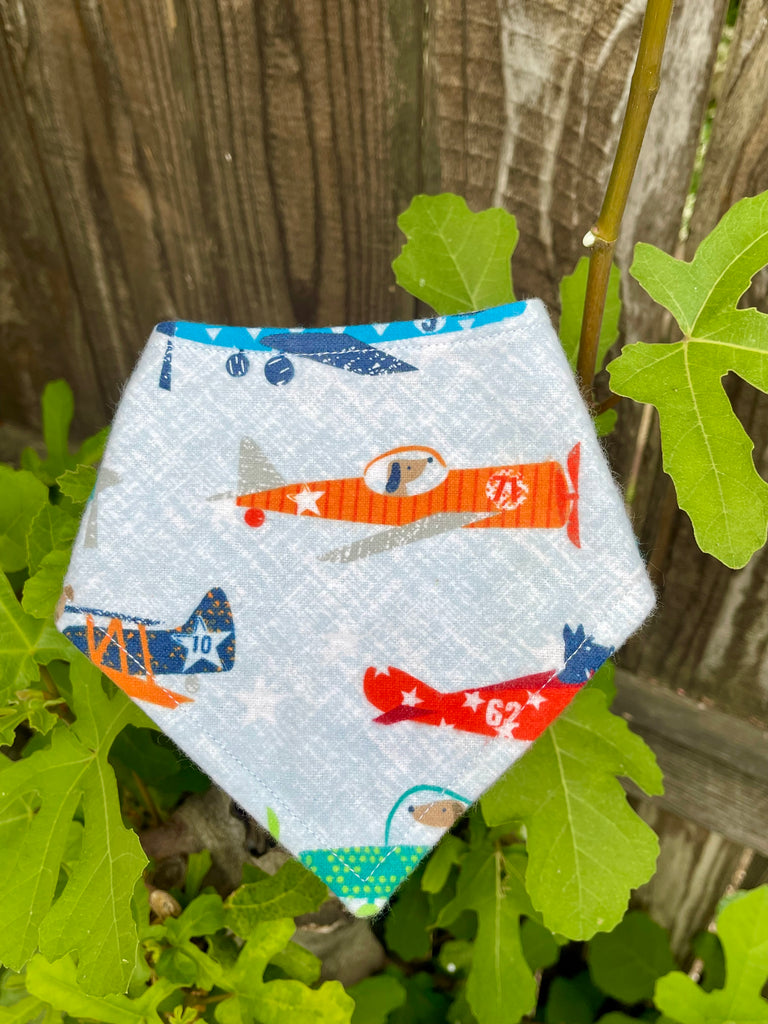 Airplane dog bandana shown on a stump with fig leaves, handmade and whimsical