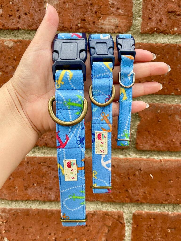 Nautical blue dog collars with anchor print and navy buckle, held in hand against red brick wall – eco-friendly and handmade