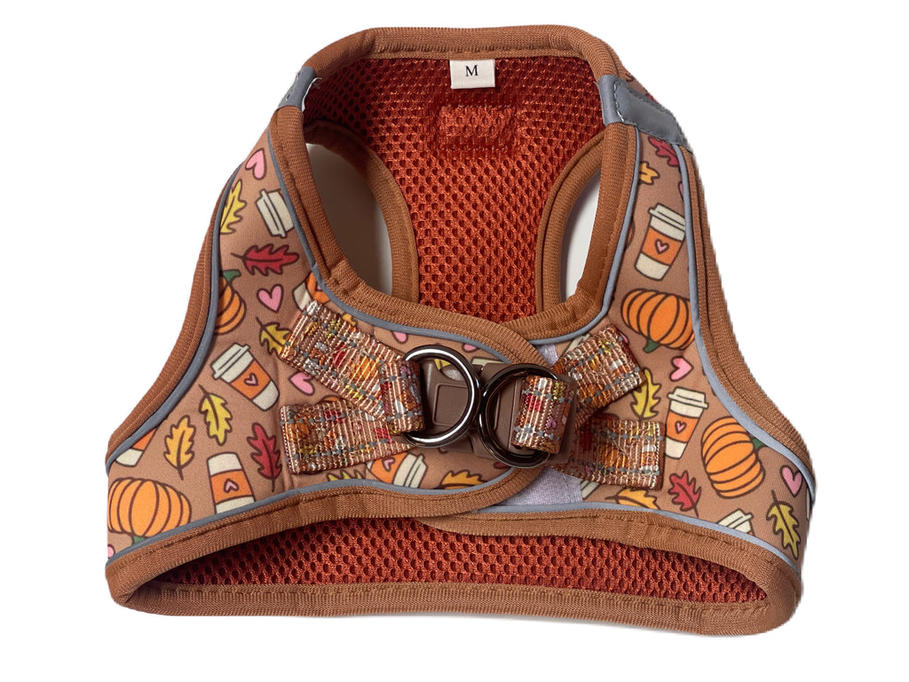 A cozy and secure dog harness vest in a festive pumpkin spice latte pattern. Features a step-in design with a velcro closure and additional buckle strap for added safety.