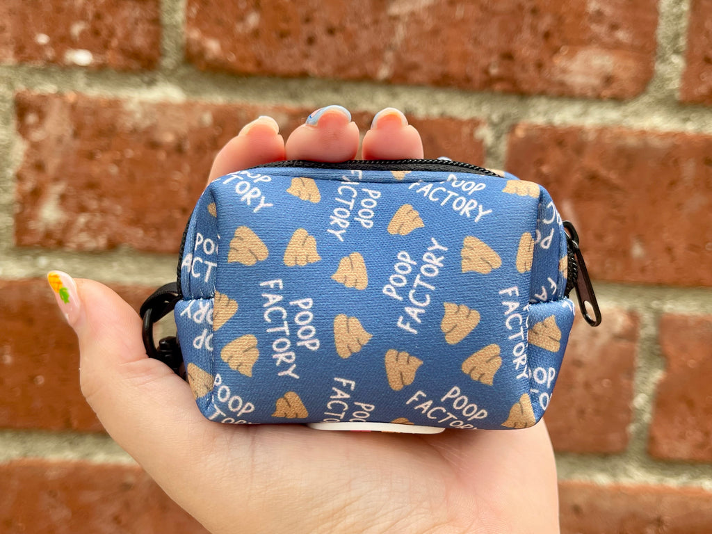Funny blue poop bag holder held in hand against red brick wall