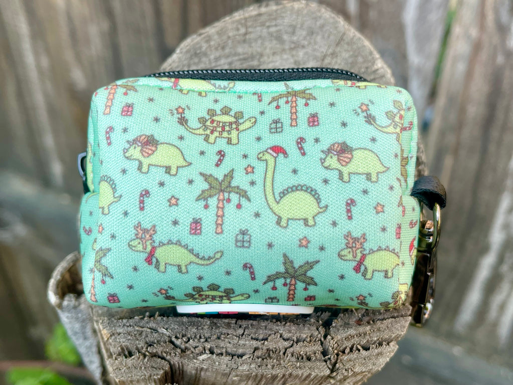 Back view of Christmas Dinos poop bag holder on stump – close-up of mint green fabric featuring dinosaurs, gifts, candy canes, and palm trees