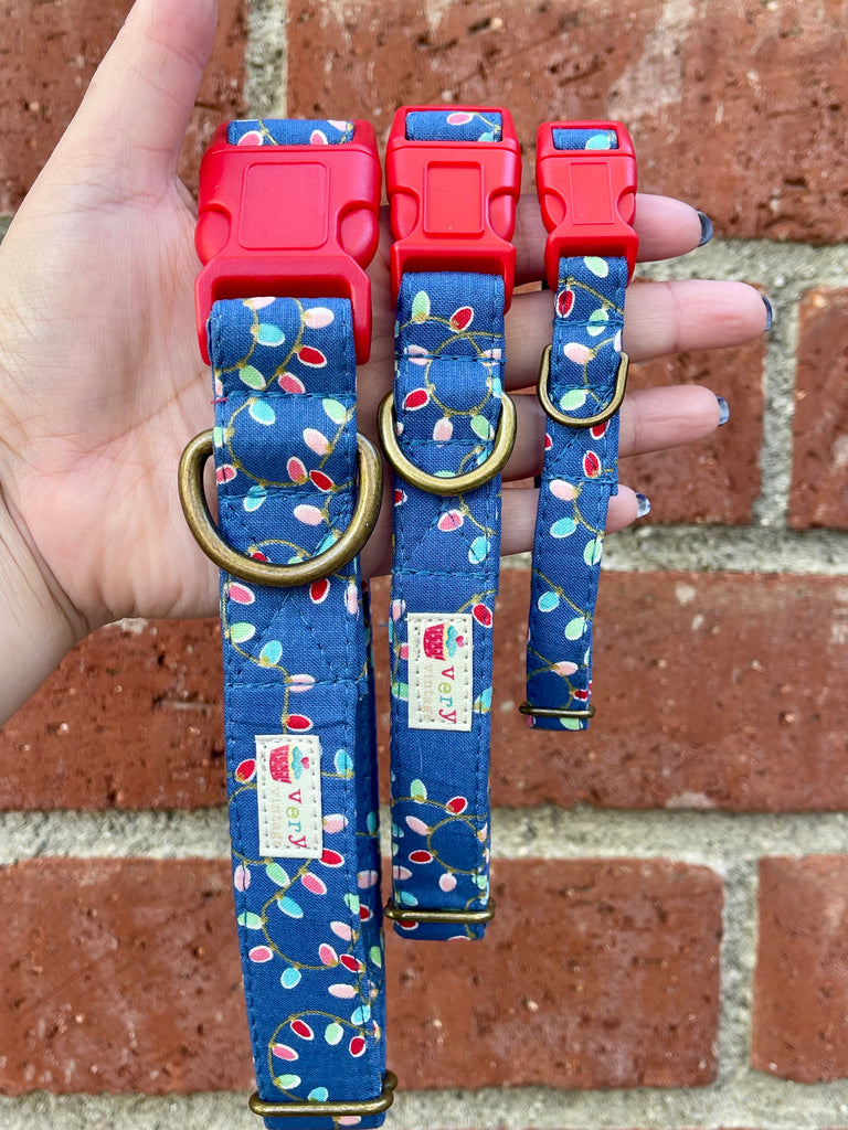 Hand holding three Christmas Lights collars in front of brick wall – handmade holiday dog collars with colorful string light print and red buckles