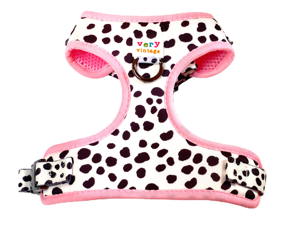 white with black cow spots adjustable dog harness with bright pink trim.