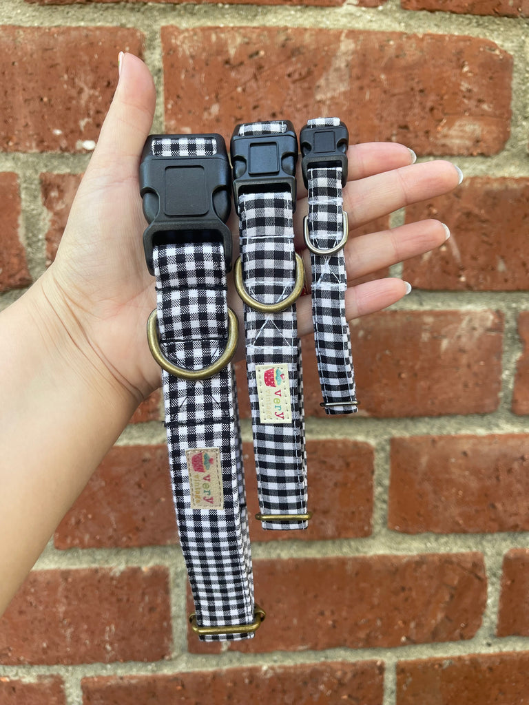 Black and white gingham dog collar with antique brass hardware, shown against a rustic brick wall. Handmade plaid pet accessory with a cozy, timeless look.