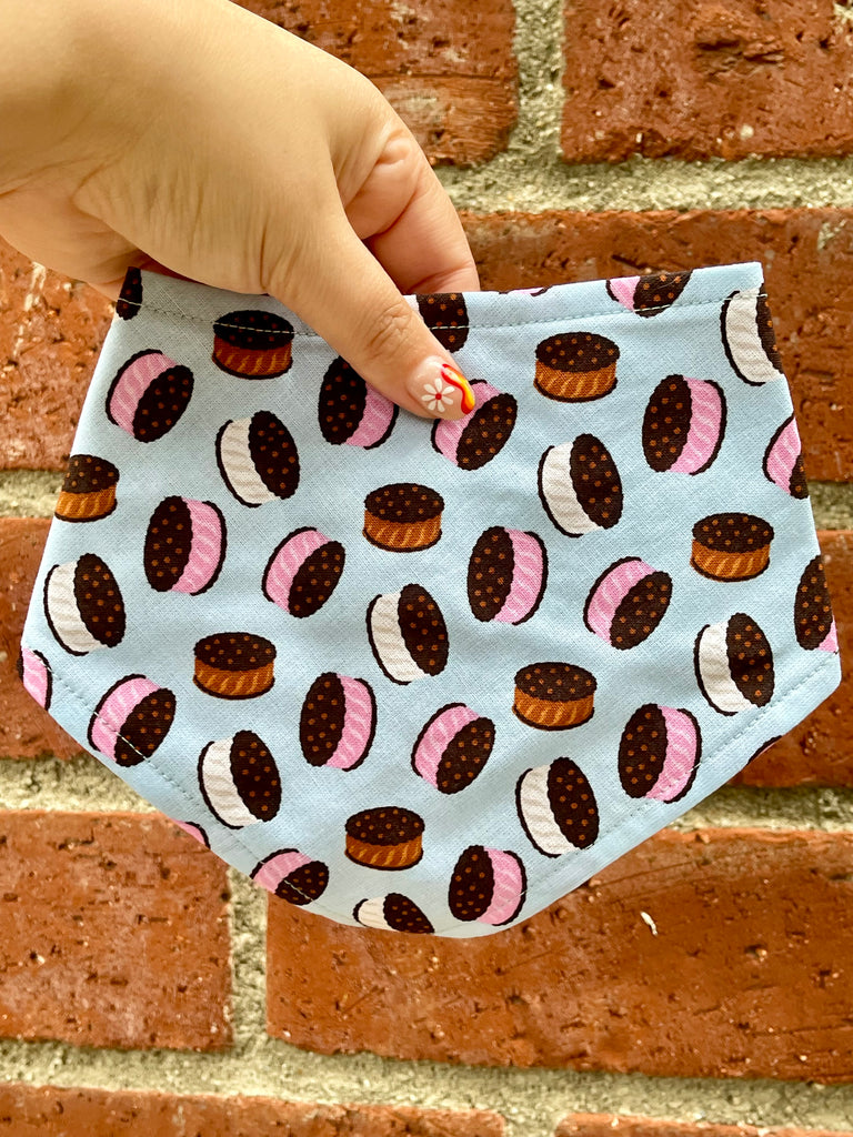 Side angle of ice cream sandwich print bandana on wood fence, capturing playful dessert pattern on pastel blue fabric. 3 snaps for an adjustable and secure fit.