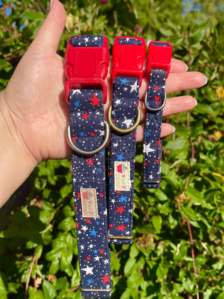 Handmade patriotic dog and cat collar with red, white, and blue star pattern on navy background, shown against a vintage brick wall. Adjustable and made in Los Angeles.