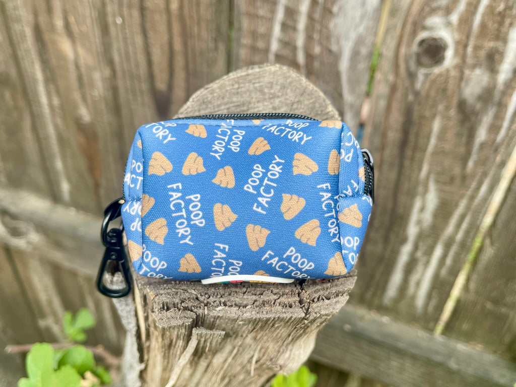 Front view of poop bag holder with poop icons, resting on wood fence