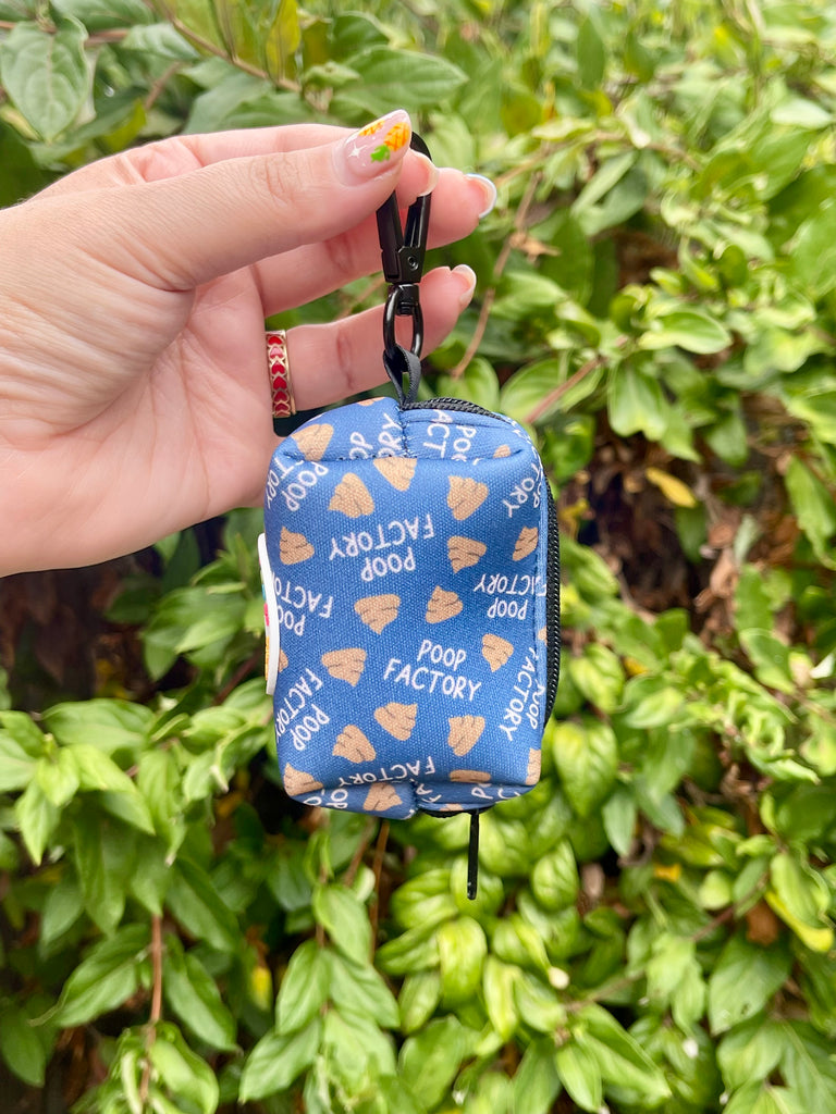Side view of poop bag holder clipped by hand, greenery backdrop