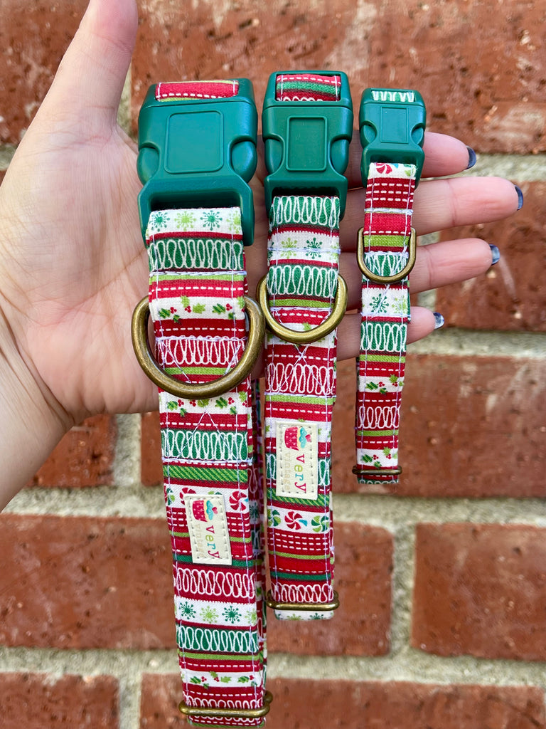Hand holding eco-friendly Christmas dog collars in front of brick wall – handmade organic cotton collars with festive ribbon candy stripe print