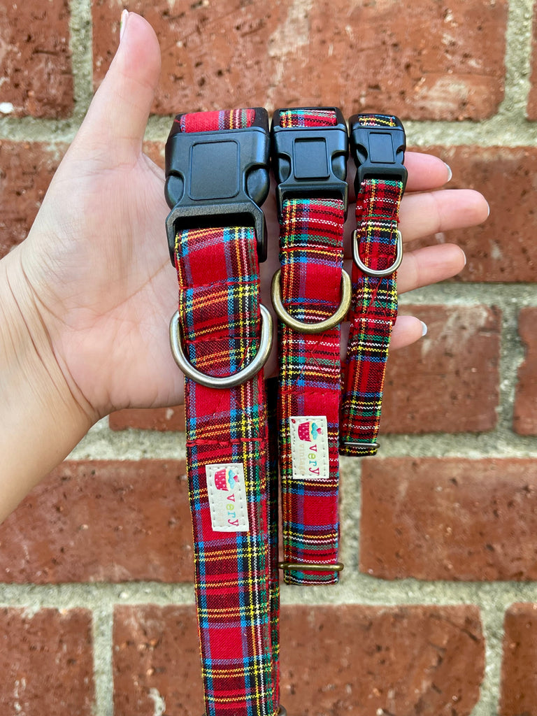 Close-up of our handmade red tartan dog collar with brass D-ring, shown against a vintage brick wall — classic, cozy, and perfect for fall walks
