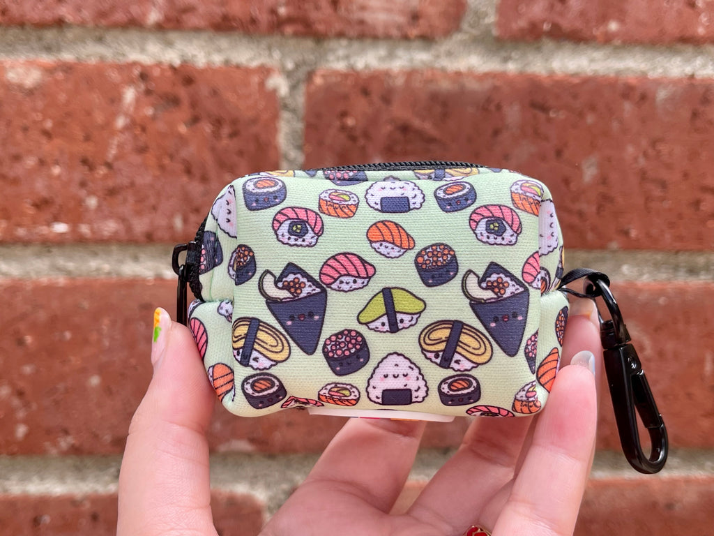 Sushi-themed poop bag holder held in front of brick wall background