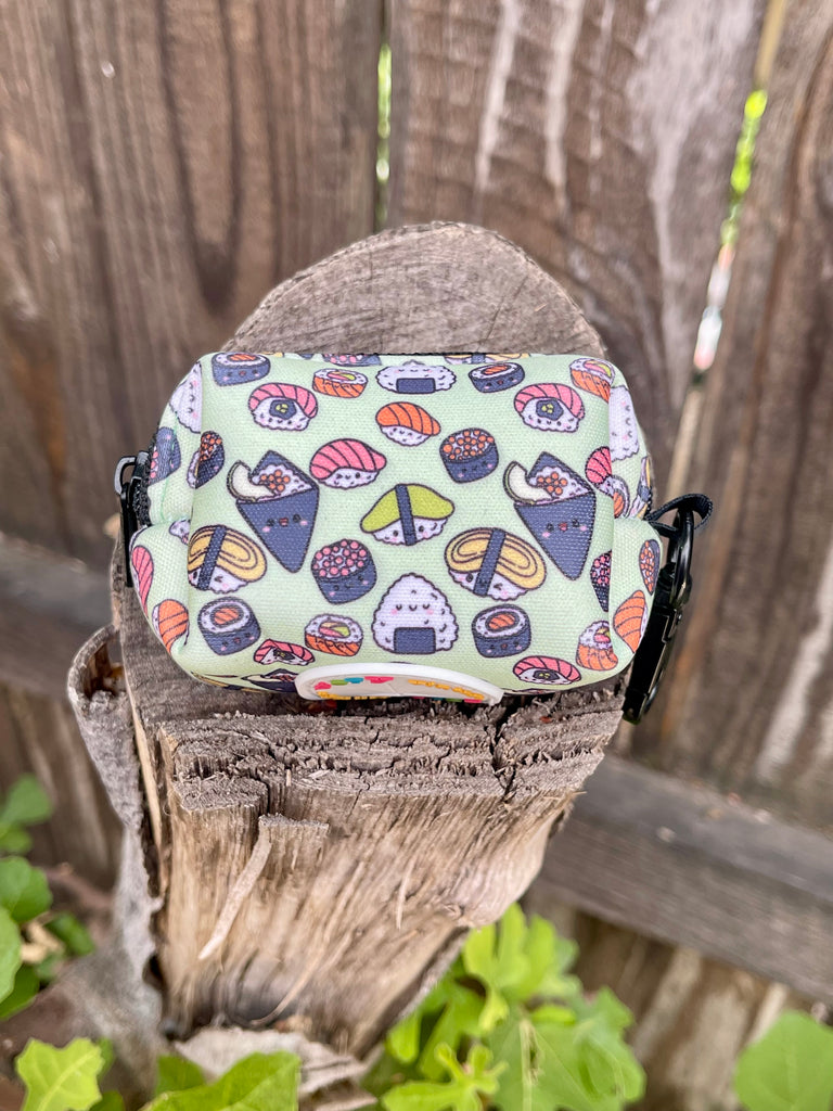 Sushi dog poop bag holder on wooden stump, front view
