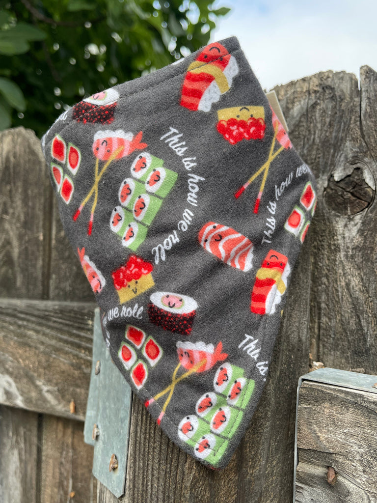 Charcoal gray dog bandana with kawaii sushi pieces, shown hanging outdoors