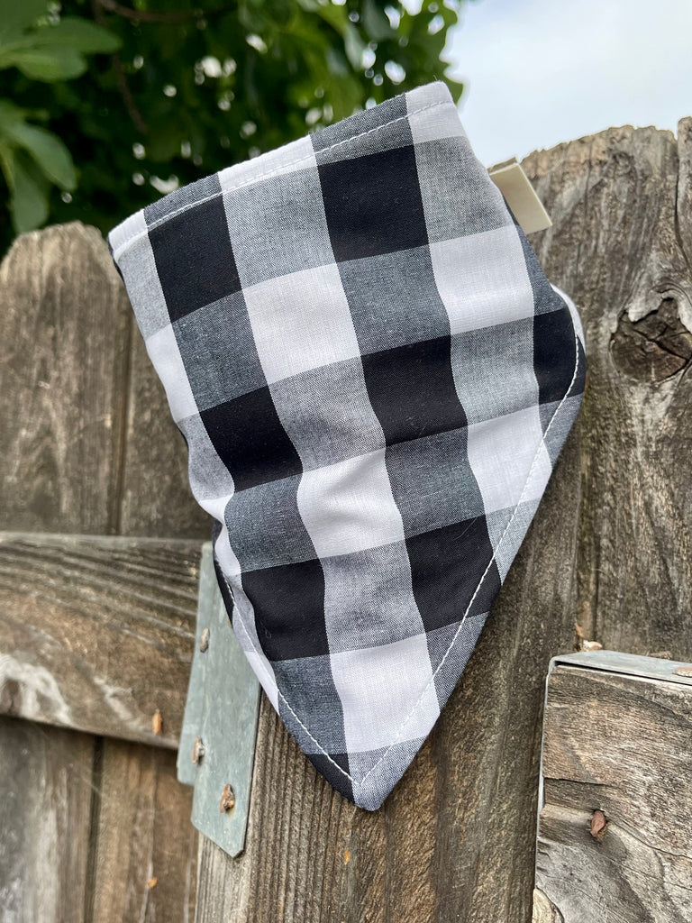 Black and white dog bandana styled on wood fence with fig leaves nearby