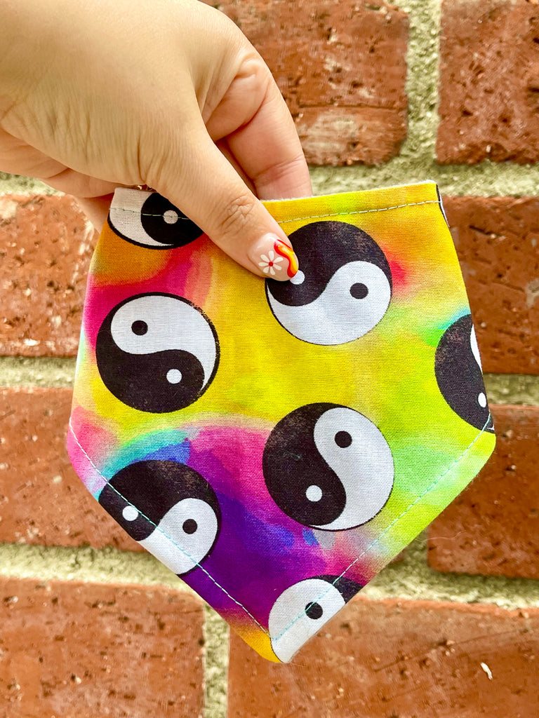 Artisan tie-dye dog bandana with yin yang print, photographed up close against a classic brick wall for product detail. Handmade in Los Angeles, California.
