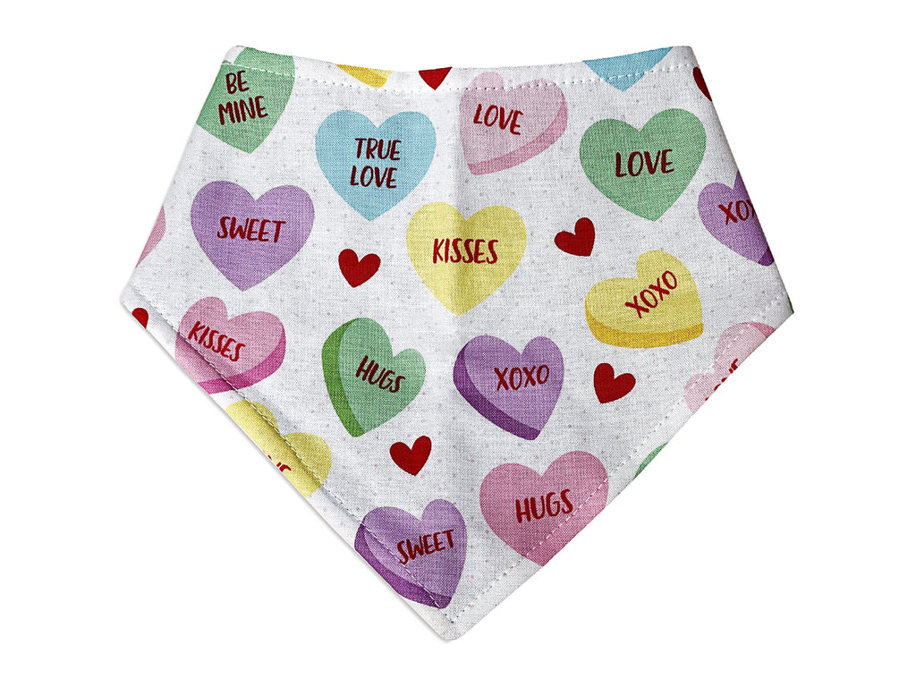 White dog bandana with a colorful conversation heart pattern. Made from organic cotton, this adjustable bandana features three snaps for a secure fit. Available in various sizes and handmade in Los Angeles.