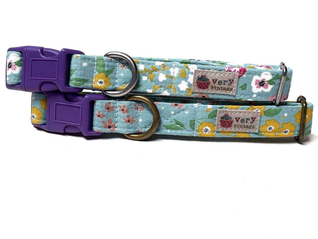 A dusty blue dog collar with vibrant, colorful flowers, made from organic cotton with antique brass or silver hardware. Handmade in Los Angeles. Perfect Spring vibes.