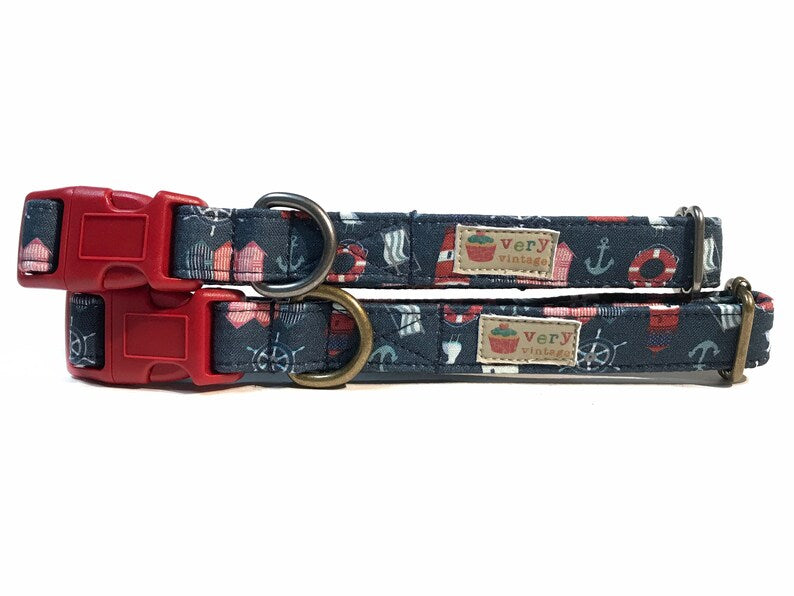 Handmade organic cotton dog collar with a navy blue background featuring an assortment of nautical items like anchors, sailboats, and lifebuoys. Perfect for summer, available in custom sizes for dogs and cats, with antique brass or silver hardware. Breakaway buckle option for added cat safety.
