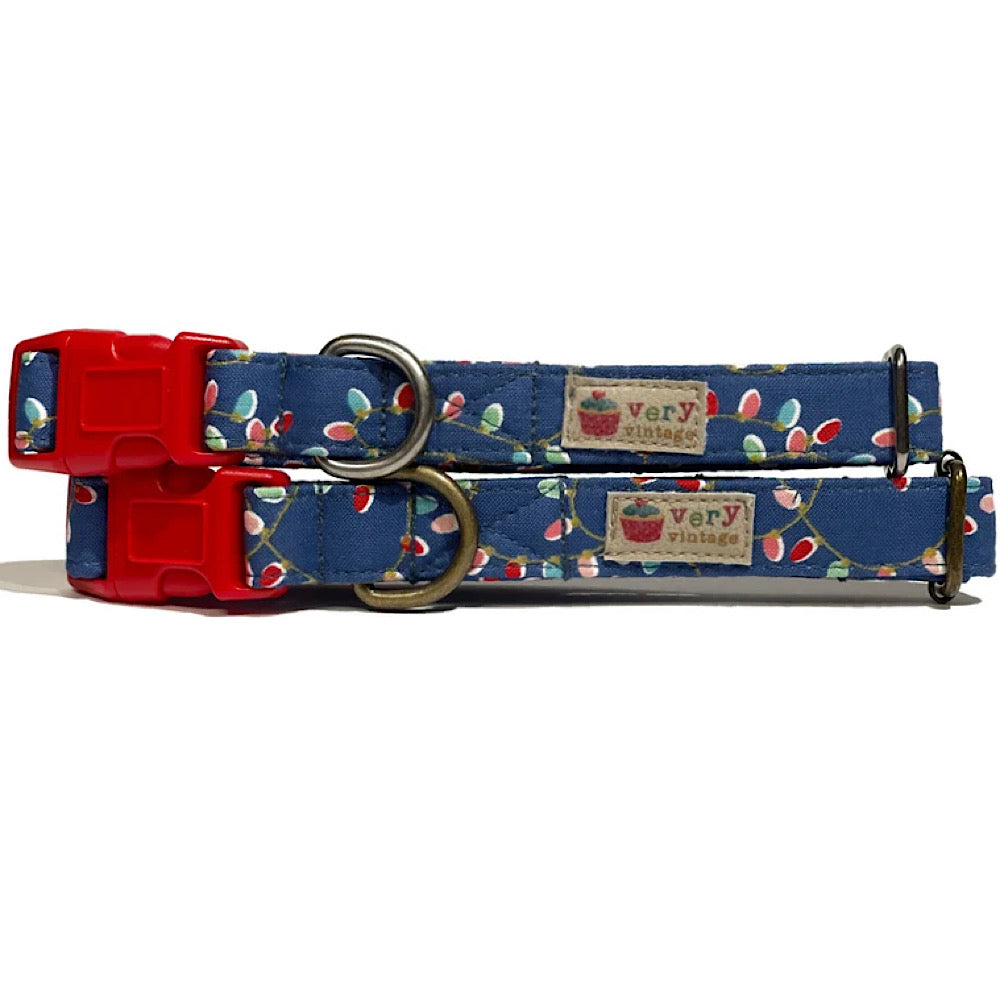 Handmade organic cotton dog collar featuring a bright blue background adorned with colorful Christmas lights. Perfect for the holiday season, available in custom sizes for dogs and cats, with antique brass or silver hardware and a breakaway buckle for added safety for cats.