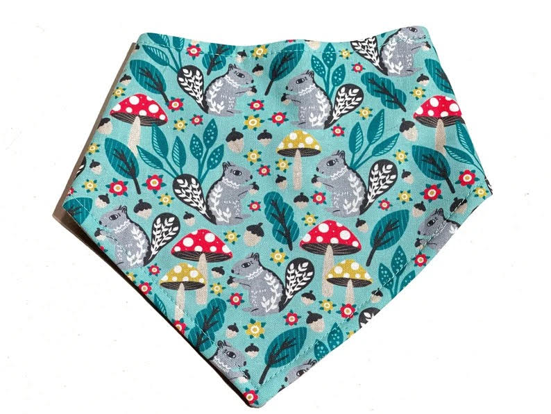 Mint green dog bandana with a playful pattern featuring gray squirrels and red and yellow toadstools.