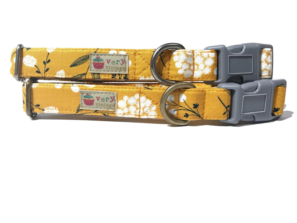 A mustard yellow dog collar featuring white flower blossoms, giving it a country vintage feel. The collar is made from organic cotton and includes antique brass or silver hardware. LA Made. 