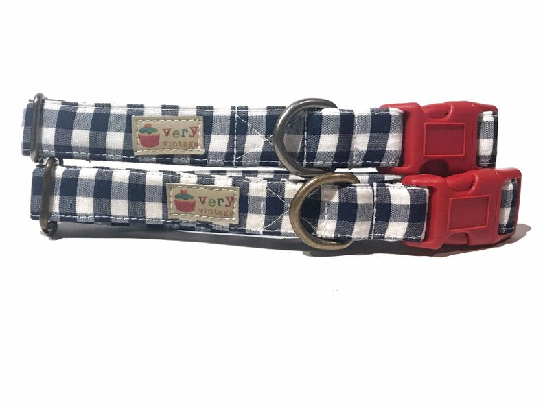 Navy blue and white gingham plaid dog collar made from soft, organic cotton. The collar features a bold red buckle accent, with high-quality antique brass or antique silver hardware options for a stylish finish. Handmade in Los Angeles, this collar is designed for comfort and durability. The perfect choice for a beachy or nautical vibe for your dog. Available in multiple sizes to fit all pups, with a breakaway buckle option for cats, ensuring safety.