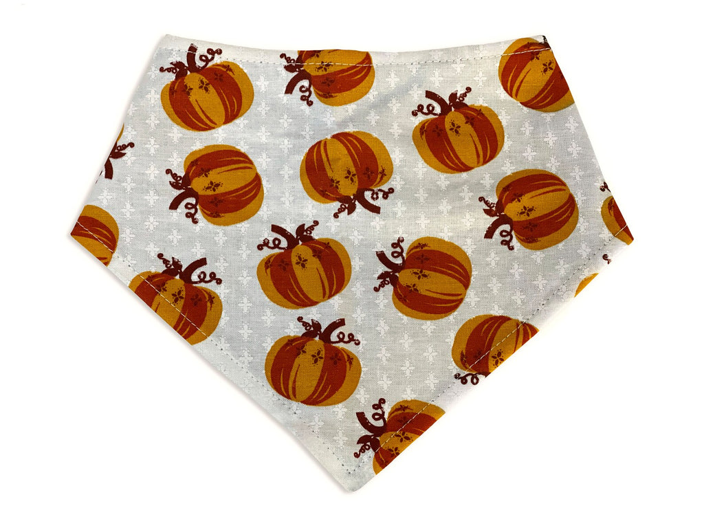 Handmade in California. A unique dog bandana with a cream background and fun orange pumpkins. 3 snaps on the back for a secure and adjustable fit.