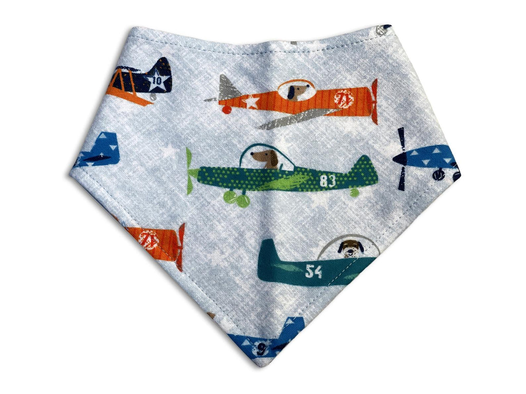 Handmade in the USA dog bandana with a light blue background with colorful airplanes and dogs piloting them. 3 snaps on the back for an adjustable and secure fit.